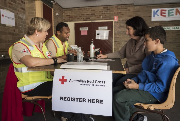 People sitting and speaking with red cross volunteers