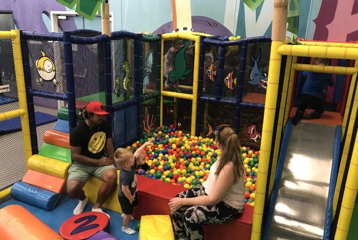 toddler in an indoor playground with his family
