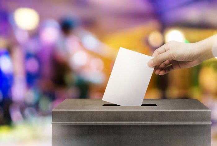 Person placing a vote in vote box