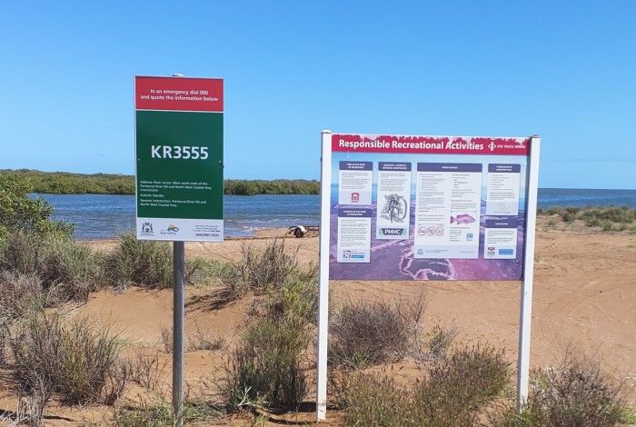 Beach emergency sign with other signs on beach shore