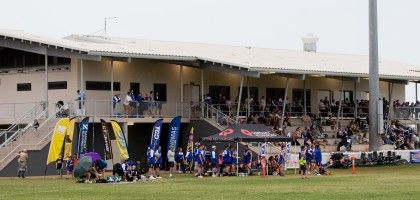A sports facility with spectators on the upper deck and teams preparing on the field, showcasing community engagement in athletics.